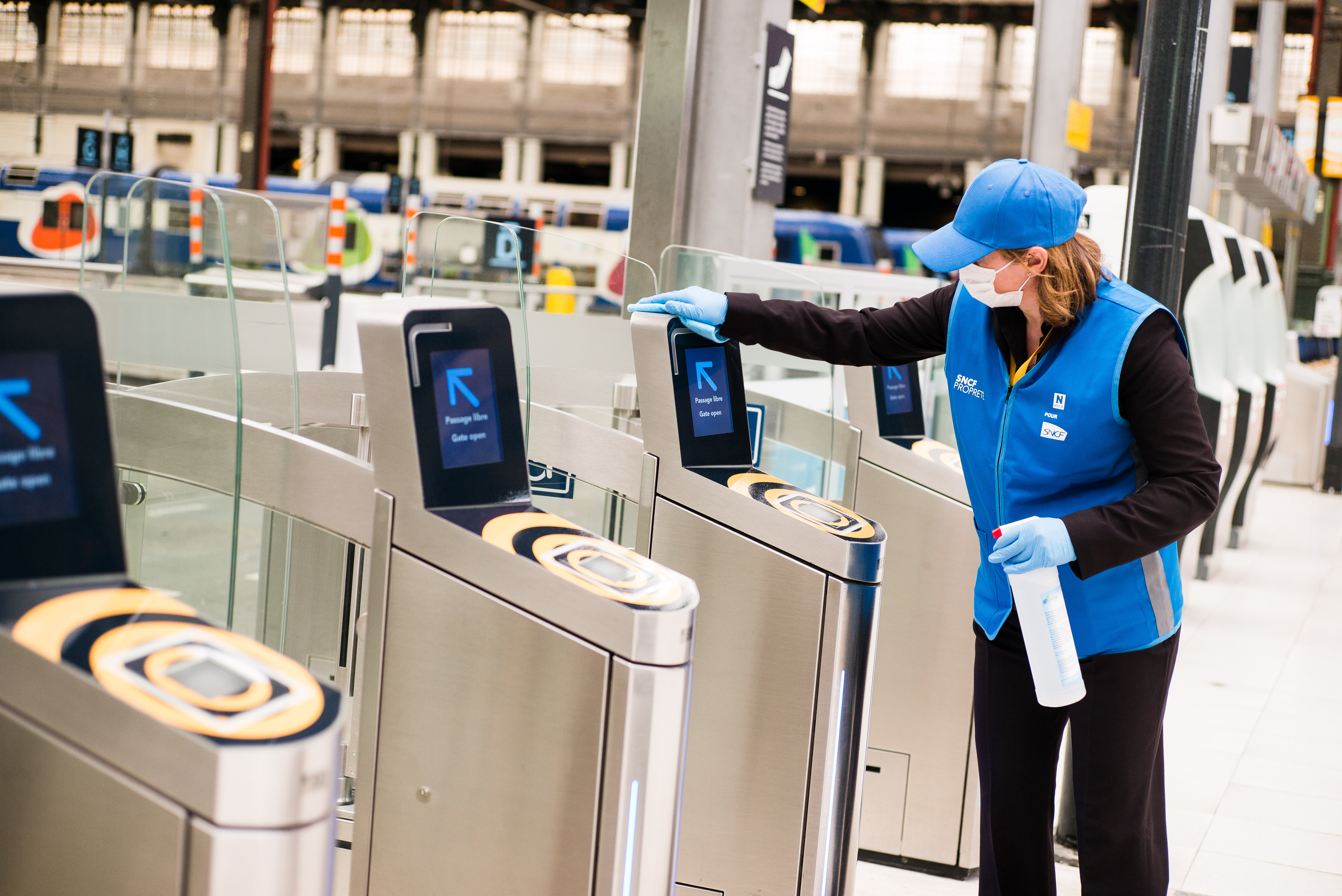 Une agent de SNCF Propreté désinfecte une porte d'embarquement à Paris Gare de Lyon
