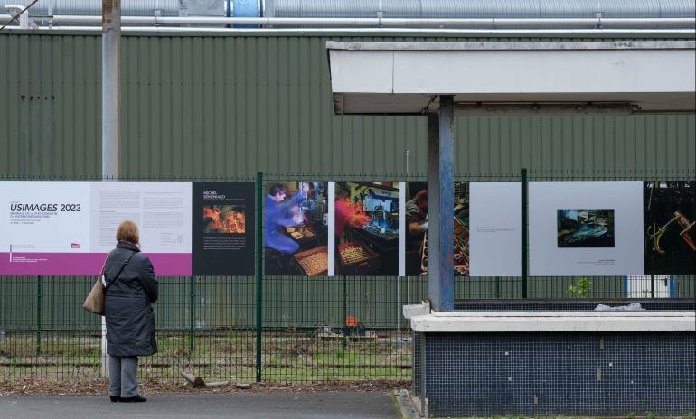 Voyageuse qui observe les panneaux de l'exposition Usimages en gare de Liancourt Rantigny
