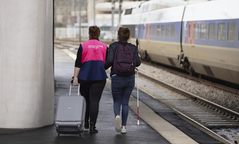 Agent SNCF assistant une personne non-voyante